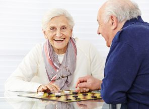 Happy senior couple playing checkers in a retirement home