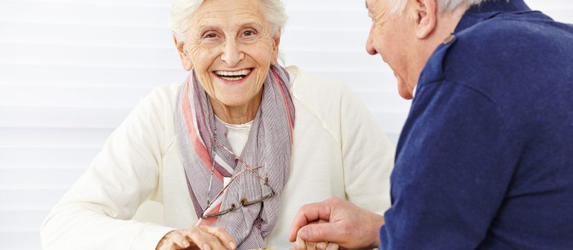 Happy senior couple playing checkers in a retirement home